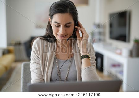 Home-office teleoperator talking on phone with headset