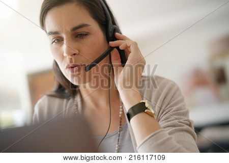 Home-office teleoperator talking on phone with headset