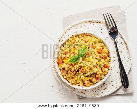 Top view of cauliflower rice with vegetables. Organic paleo Cauliflower Rice with corn, green peas and carrots on white concrete background. Copy space.