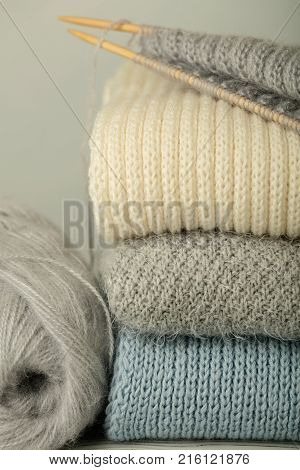 Handmade knitting and woolen thread. Pile of knitted clothes blue white and gray colors. Selective focus.