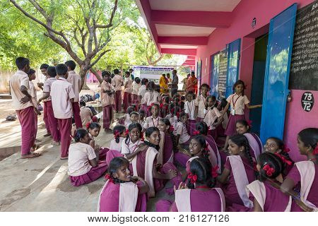 PONDICHERY PUDUCHERY INDIA - SEPTEMBER 04 2017. Outdoor meeting of the children of the school with uniforms sitting on the floor waiting for sport equipments as a gift from an association.