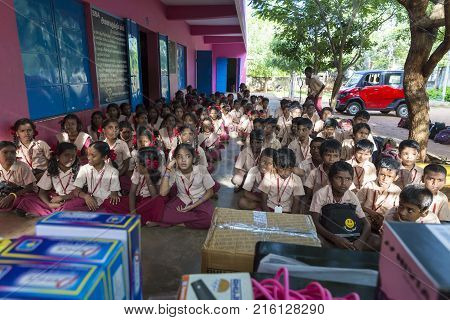PONDICHERY PUDUCHERY INDIA - SEPTEMBER 04 2017. Outdoor meeting of the children of the school with uniforms sitting on the floor waiting for sport equipments as a gift from an association.