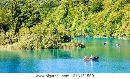 Plitvice Lakes National Park, Croatia - August 30, 2017: Park visitors enjoying evening row boat ride on a lake in Plitvice Lakes National Park, Croatia