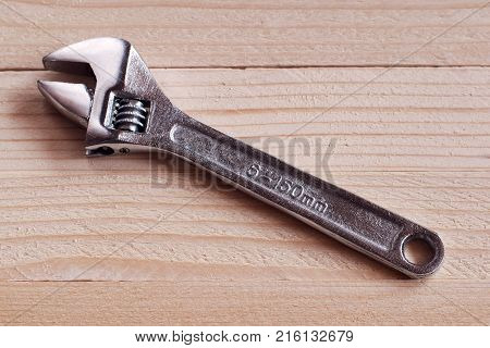 Chrome-plated adjustable wrench on a wooden background