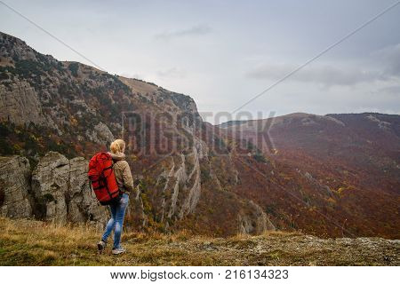 Girll at the top of a mountain looks at the valley enjoying the view