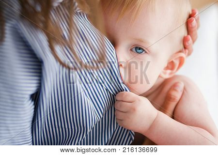 Baby is fed mother's milk looking at camera. Close up head shot.