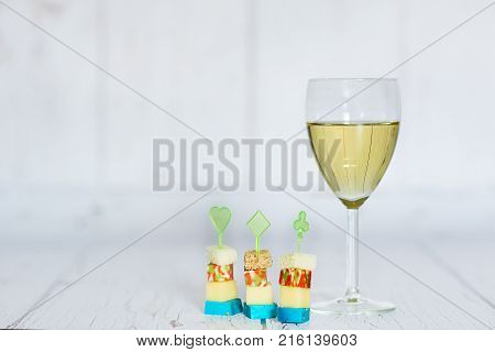 Glass of white wine, polenta with cherry tomato and chese canapes on a wooden background