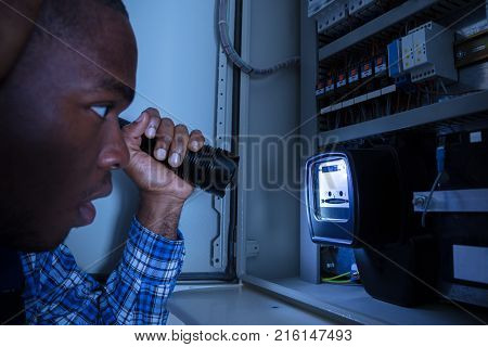 Close-up Of A Electrician Examining A Electric Meter With A Torch