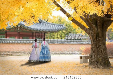 Asian Korean woman dressed Hanbok in traditional dress walking in Gyeongbokgung Palace in autumn season at Seoul South Korea.