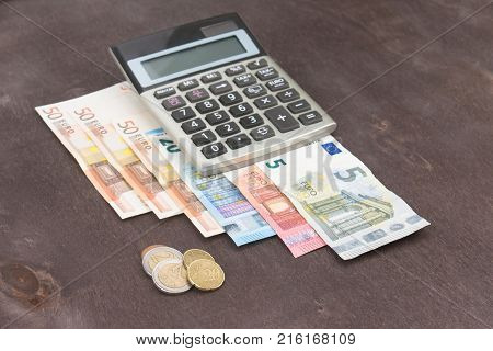 Banknotes and coins with calculator. Euro banknotes on wooden background. Photo for tax profit and costing. 50 euro 20 euro 10 euro. Money and finance