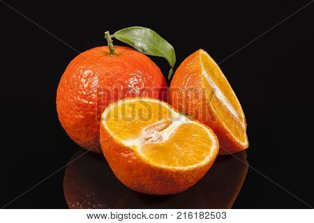 Fruits of mandarin orange whole and cut on black background reflection