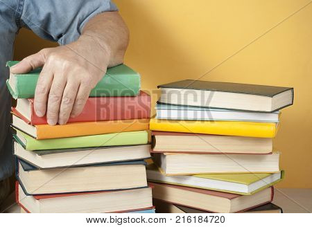 Education concept.Hand of man on stack of colorful books