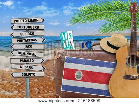 Concept of summer traveling with old suitcase and Costa Rica town sign
