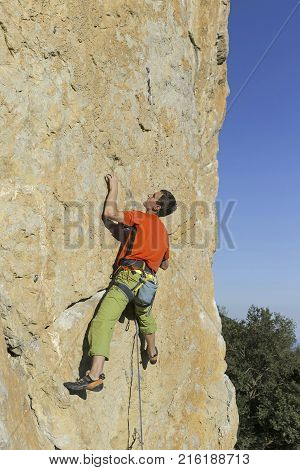 A man rock climbing on rocks against the background of the sea.