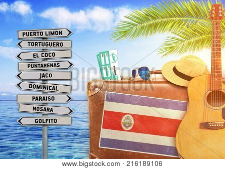 Concept of summer traveling with old suitcase and Costa Rica town sign with burning sun