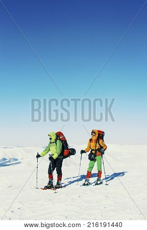 Winter hike in the mountains two men are walking along the snow ridge.