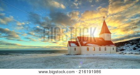 Typical red colored wooden church in Vik town, Iceland in winter. Sunrise light