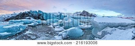 Iceberg lagoon in Fjallsarlon, Iceland. Panoramic view of beautiful sunset light, concept of global warming and ice melting.