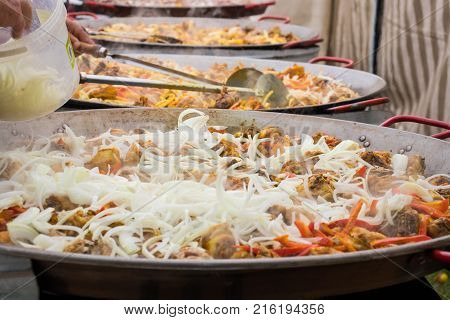 Making a giant paella. Etap add onions.