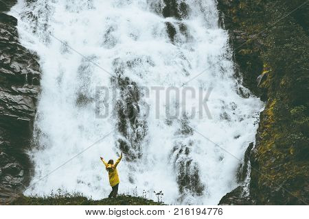 Woman happy raised hands at big waterfall outdoor Travel Lifestyle success concept adventure scandinavian vacations in Norway