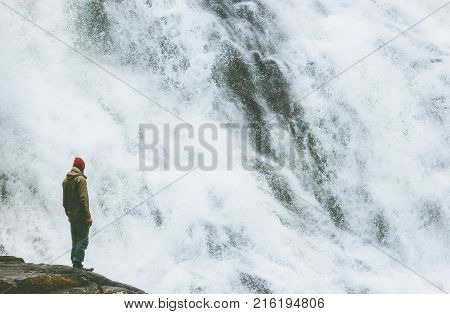 Man standing on cliff at big waterfall outdoor Travel Lifestyle success concept adventure scandinavian vacations in Norway
