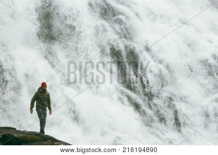 Man tourist hiking at big waterfall outdoor Travel Lifestyle success concept adventure scandinavian vacations in Norway wild nature