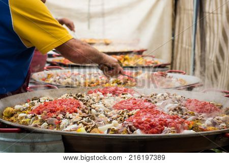 Giant paella in preparation. Added tomatoes and seafood.