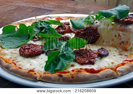 Pizza with mozzarella, rucula and dried tomato