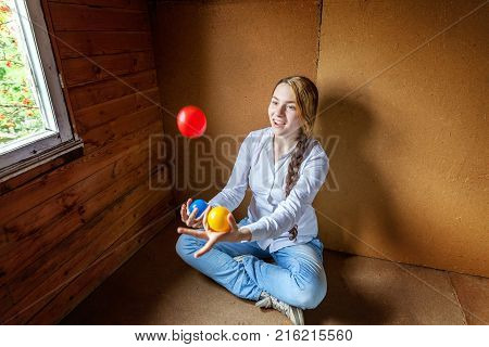 beautiful young smiling woman sitting and juggling