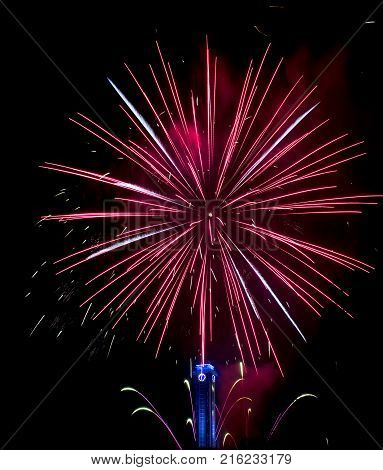 Red silver gold fireworks in Ostrava. The black sky illuminates the fireworks in the background is a blue clock at the Ostrava city hall in the Czech Republic.
