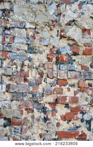 old decaying brick wall with repairs and crumbling cement layer