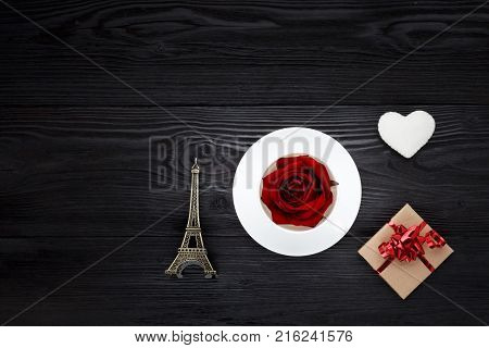 White cup with Eiffel tower and gift box on black table. Concept for Valentine's day greeting card.