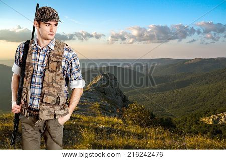 Male hunter rifle green red background sky