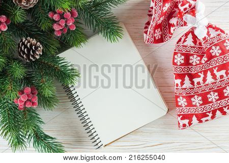 New Year background with Christmas tree and empty note greeting card on white wooden surface. Top view.