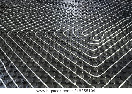 Radiant underfloor heating installation with flexible tubing mounted on insulation boards