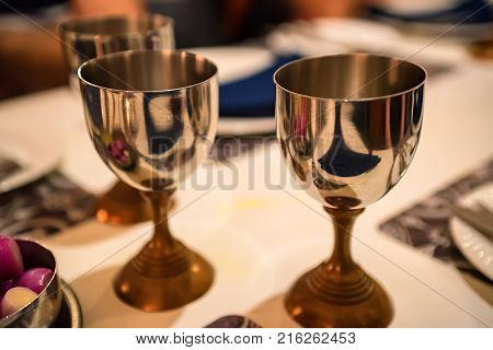 Close up image of several metal wine glasses on table in restaurant with blurred background