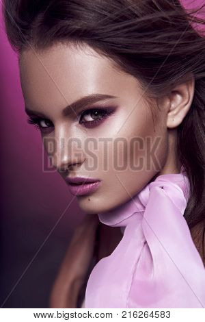 Beautiful Fashionable Girl Haired With Long Curly Hair Posing With A Pink Bow. The Girl In The Studi