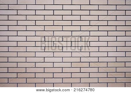 Wall of a new, level brick. The color of the brick is light beige. Sutures are thin, even, dark in color. Texture. Background.