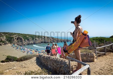 View of the beach of Calamosche Vendicari in Sicily - Tourists families sunbeds and umbrellas on summer hot day