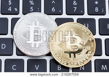 Digital currency physical silver and golden bitcoin coins on black computer keyboard. High resolution photo.