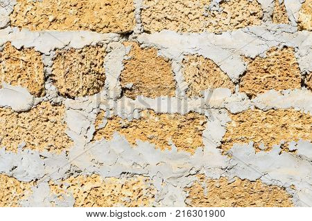 Wall building stone limestone four rows yellow closeup with a big cement layer