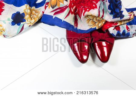 Toes of women's ruby red patent leather shoes with bows draped with a colorful floral woman's scarf horizontal aspect