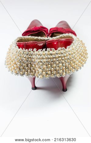 Woman's vintage faux pearl collar draped over vintage ruby red shoes rear view copy space vertical aspect