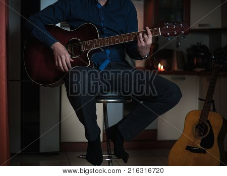The Guitarist Guy plays the guitar in a bar in a beautiful setting on a high bar stool