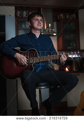 The Guitarist Guy plays the guitar in a bar in a beautiful setting on a high bar stool