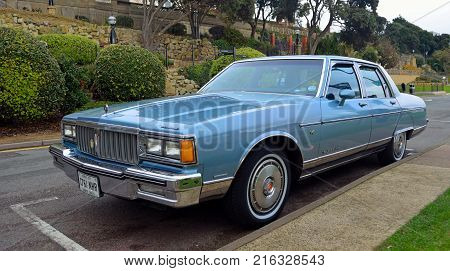 FELIXSTOWE, SUFFOLK, ENGLAND - NOVEMBER 05, 2016: Classic Pontiac Parisienne V6 Parked with gardens in background.
