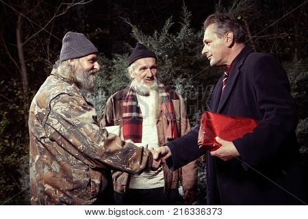 Two homeless older men rewarding manager man for gift of food