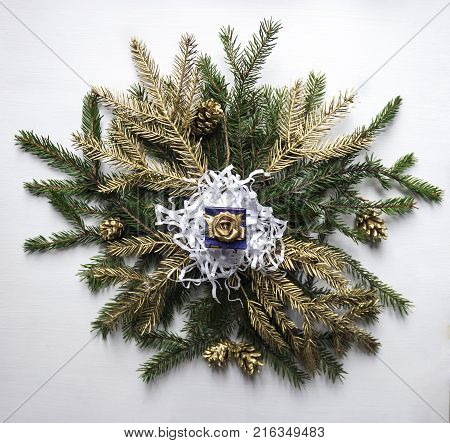 on a wreath of fir branches and golden twigs and cones lies a Christmas gift holiday winter