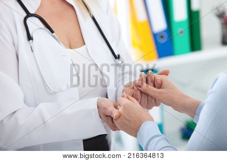 Hand of doctor reassuring her female patient. Medical ethics and trust concept