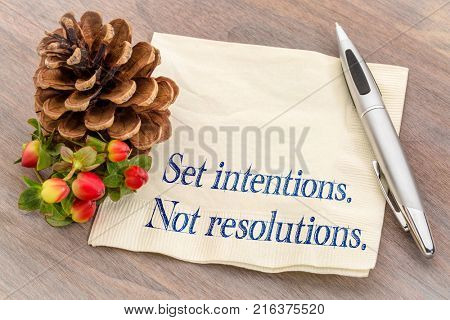 Set intentions. Not resolutions. New Year goals concept.  Handwriting on a napkin with a pine cone.